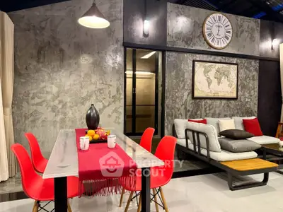 Stylish modern living room with industrial decor, red chairs, and a cozy seating area, perfect for entertaining.