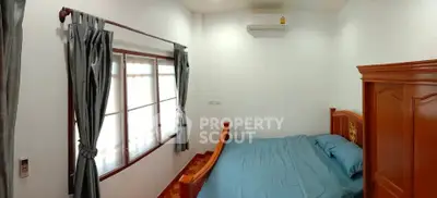 Cozy bedroom with wooden bed frame and blue bedding, featuring large windows and air conditioning.