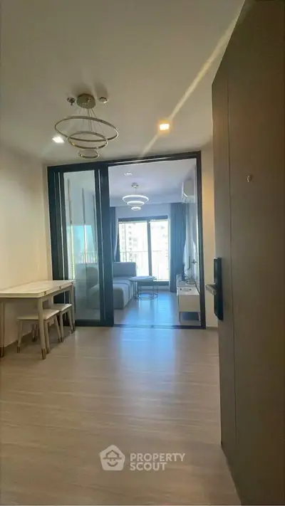 Modern apartment entrance leading to a stylish living room with large windows and elegant lighting.
