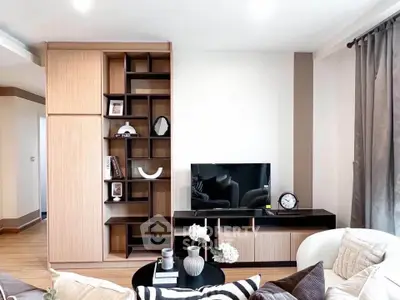 Modern living room with stylish shelving and TV unit, featuring elegant decor and cozy seating area.