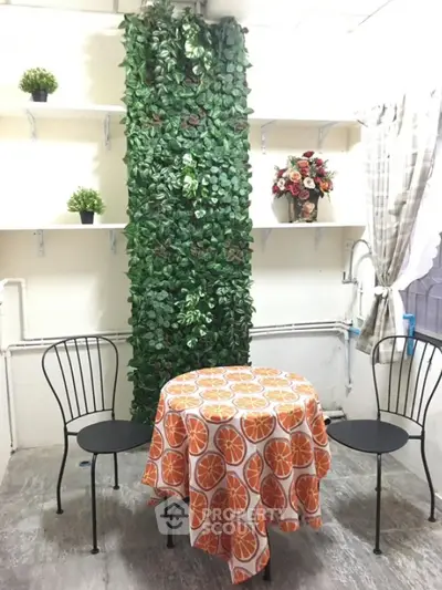 Charming small dining area with vibrant tablecloth and lush green decor