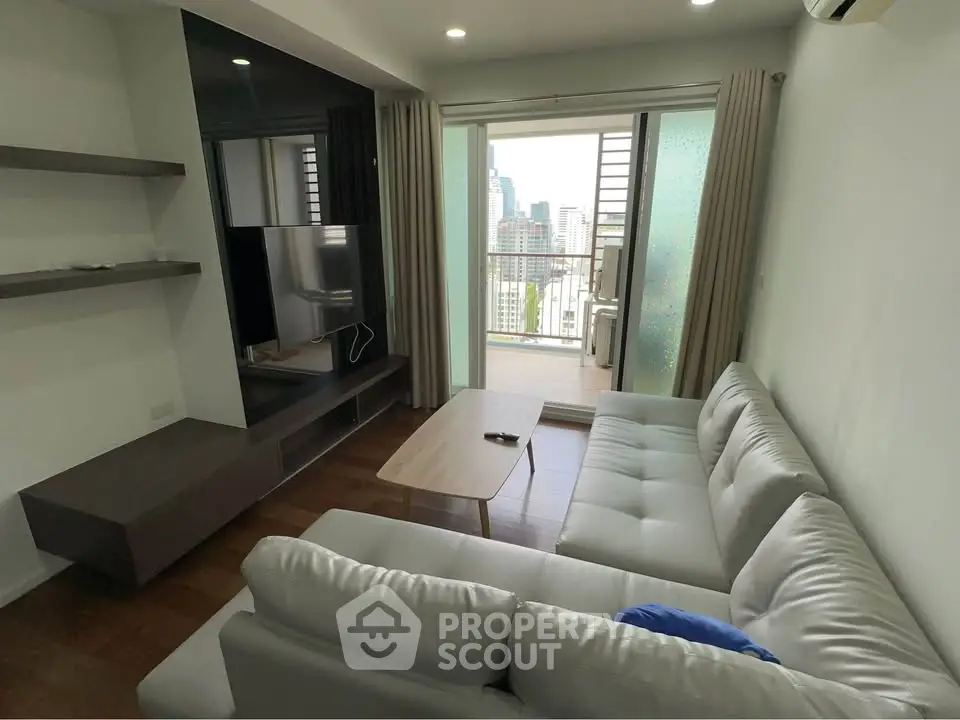 Modern living room with large sofa and city view balcony in high-rise apartment.
