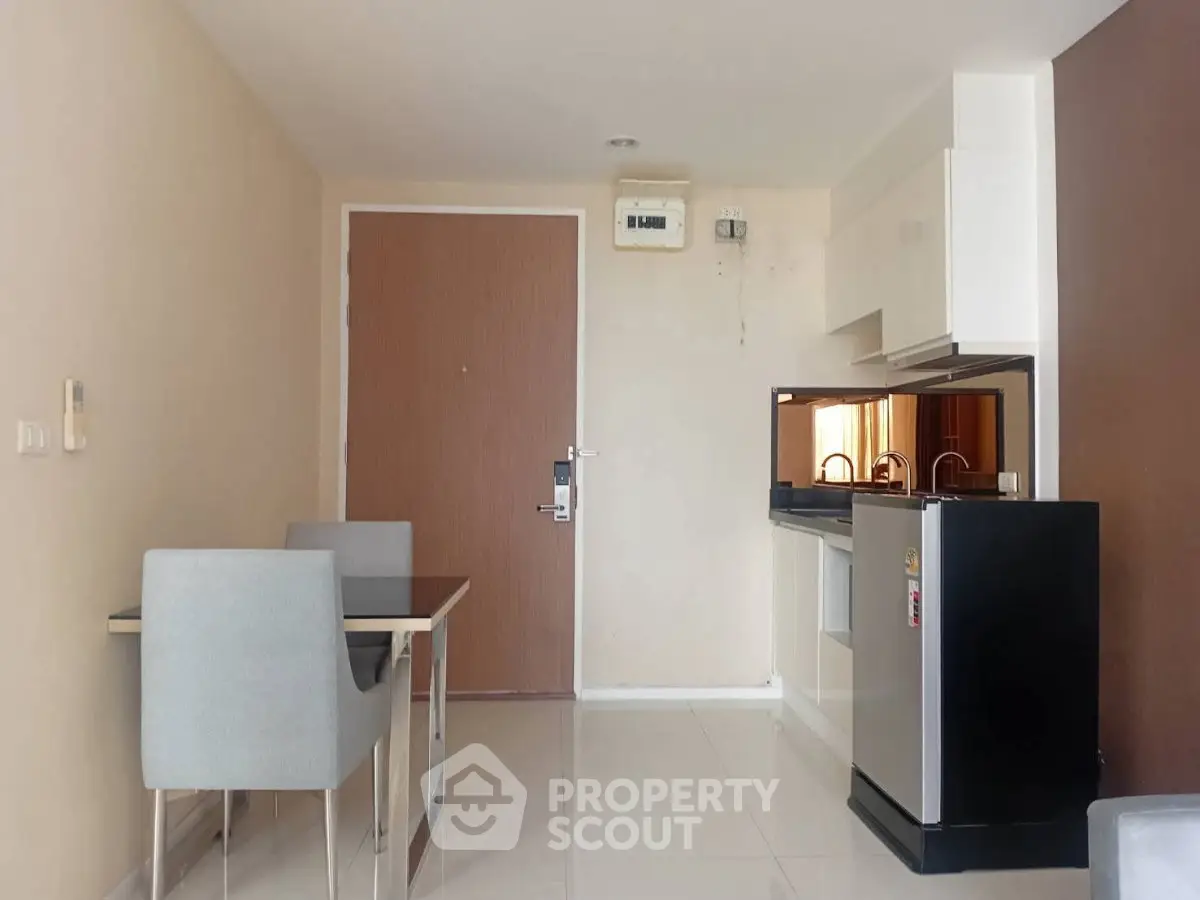 Modern apartment interior with compact kitchen and dining area, featuring sleek design and neutral tones.