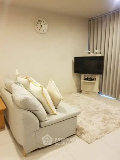 Cozy living room with plush sofa, wall-mounted TV, and elegant decor.