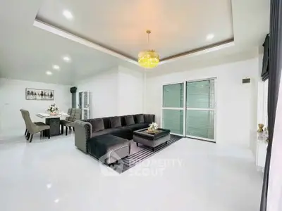 Spacious modern living room with elegant decor and dining area, featuring a luxurious chandelier.