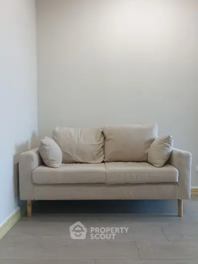 Minimalist beige sofa in a modern living room with wooden flooring.