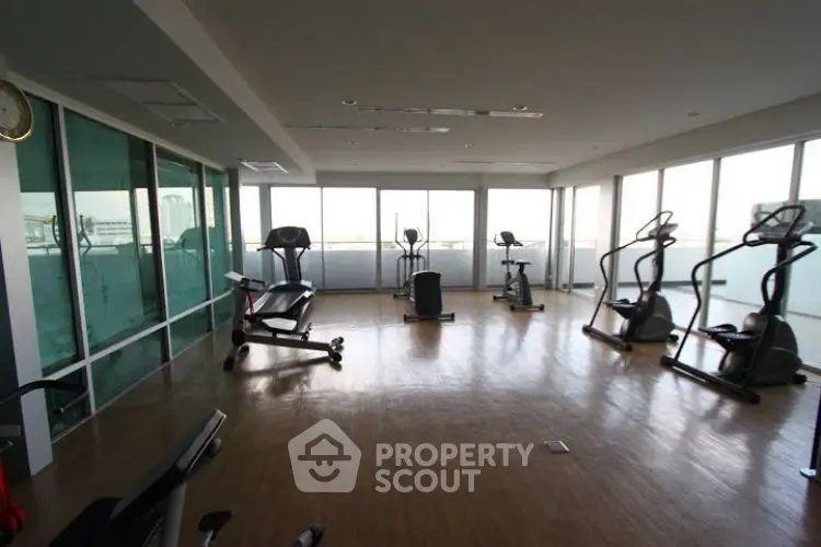 Spacious gym with modern equipment and panoramic windows in luxury building.