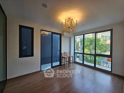 Spacious room with elegant chandelier and large windows offering natural light.