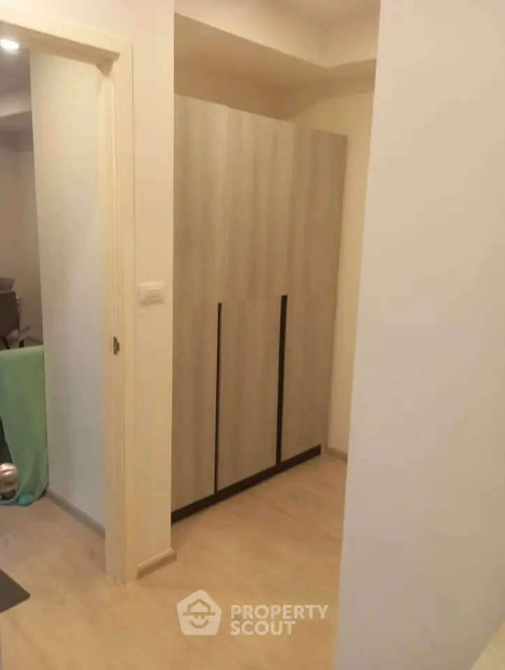 Modern apartment interior with sleek wooden wardrobe and light flooring.