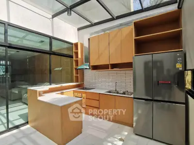 Modern kitchen with sleek wooden cabinets and stainless steel appliances in a sunlit space.