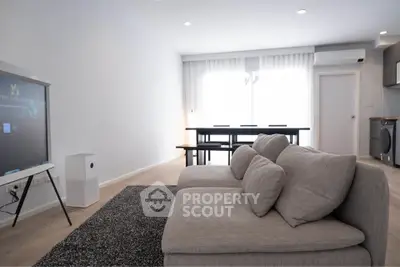 Spacious modern living room with cozy sofa and dining area, featuring sleek design and ample natural light.