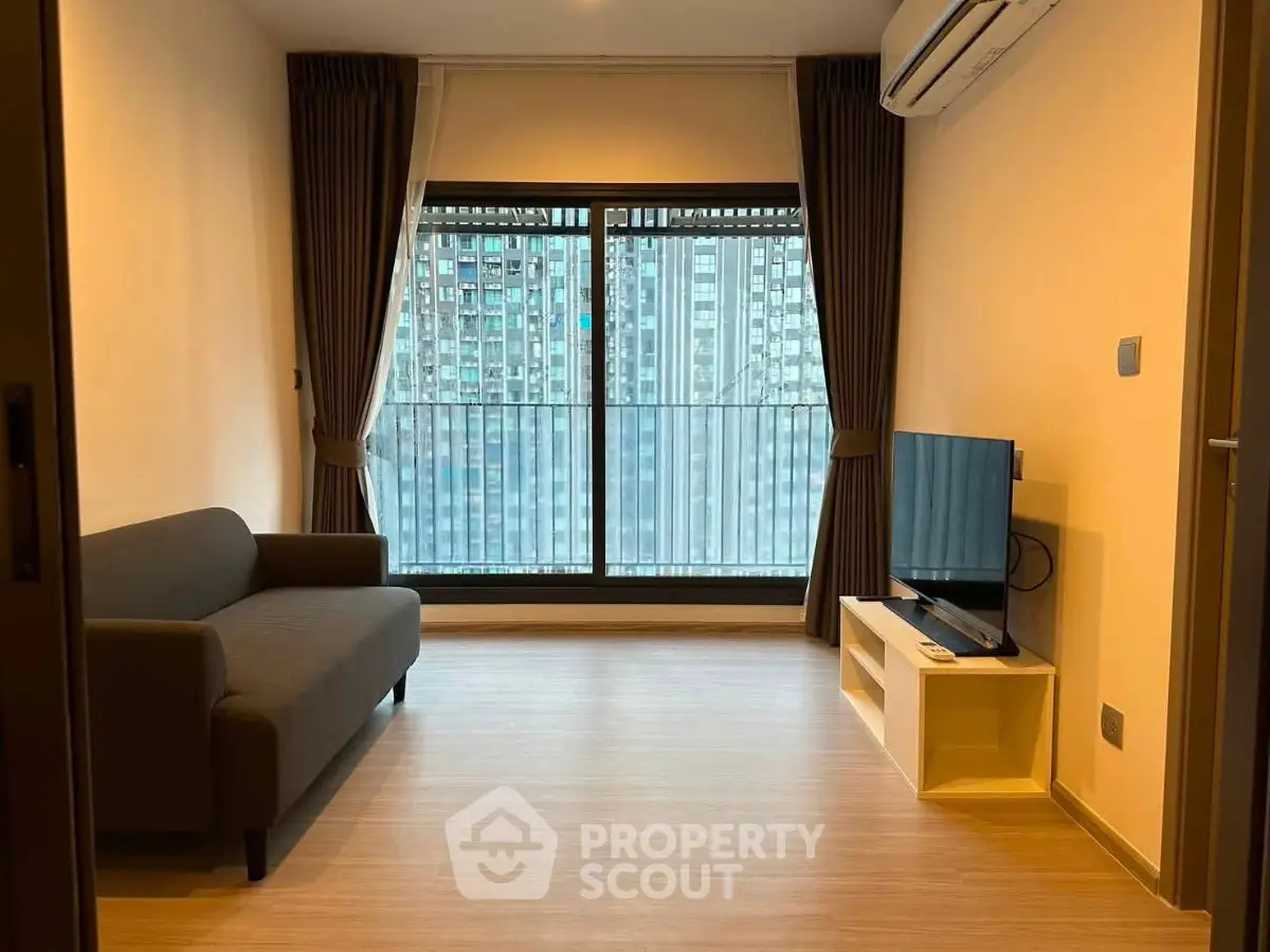 Modern living room with large window and city view, featuring a sleek sofa and wall-mounted TV.