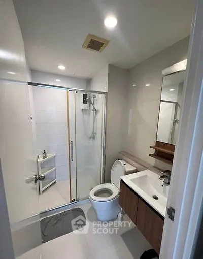 Modern bathroom with glass shower and sleek fixtures in contemporary apartment.