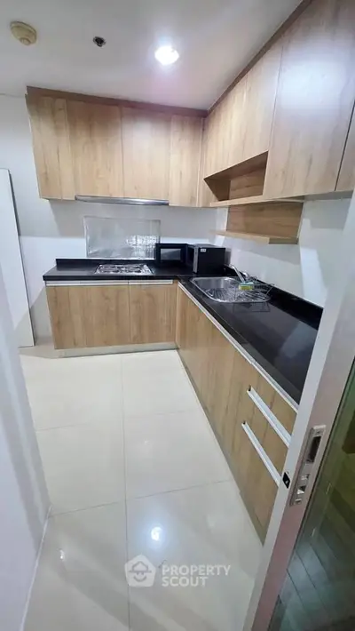 Modern kitchen with sleek wooden cabinets and black countertops in a contemporary apartment.