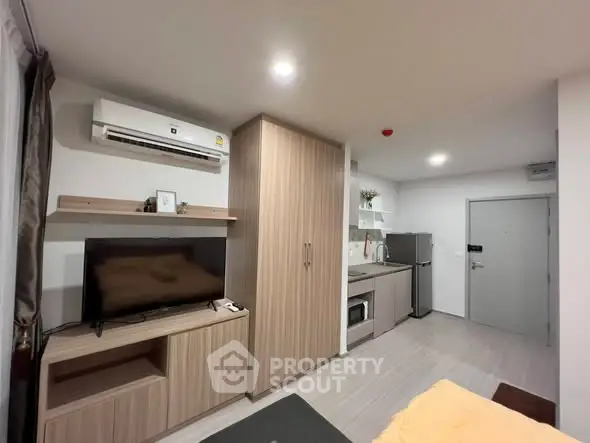 Modern studio apartment with sleek kitchen and cozy living area, featuring air conditioning and stylish wood finishes.