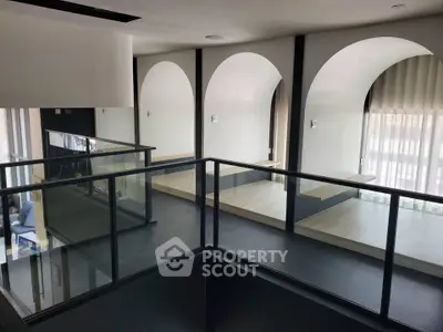 Modern interior with arched windows and sleek glass railing, perfect for contemporary living.