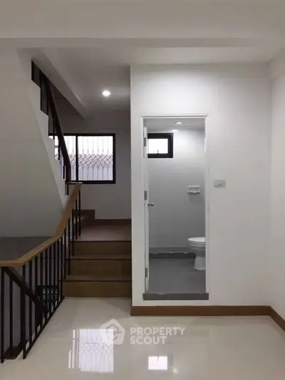 Modern interior with staircase and small bathroom, featuring sleek design and neutral tones.