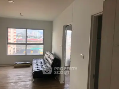 Modern apartment interior with large window and stylish black sofa, offering city views.
