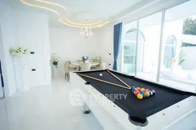 Luxurious living room with pool table and elegant dining area, featuring modern decor and large windows.