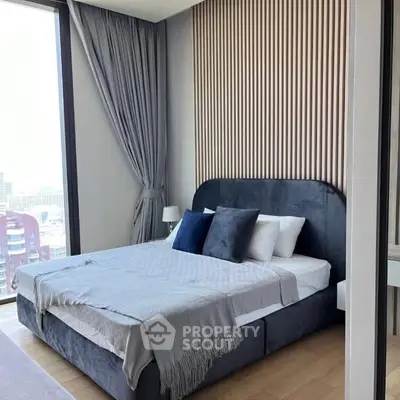 Luxurious bedroom with modern decor and large window offering stunning city views.