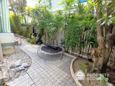 Charming garden with lush greenery and paved walkway in a serene residential setting.