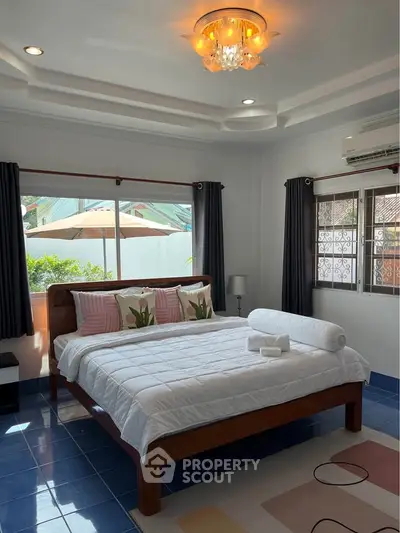 Spacious bedroom with elegant decor and natural light, featuring a cozy bed and stylish lighting.