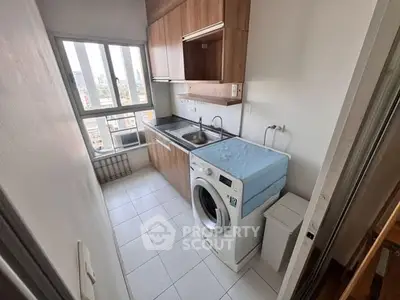 Compact kitchen with washing machine and large window offering city view.