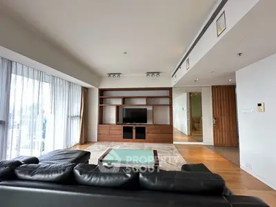 Spacious modern living room with sleek black leather sofa and built-in entertainment center.