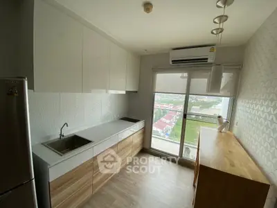 Modern kitchen with sleek cabinets and city view from large window.