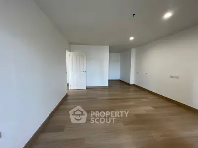 Spacious empty room with wooden flooring and white walls, ideal for customization.