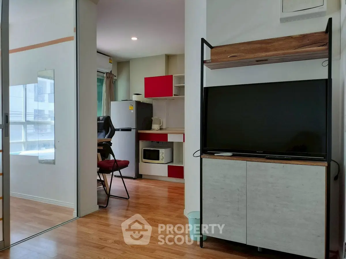 Modern apartment interior with open kitchen and living area featuring sleek furniture and wooden flooring.