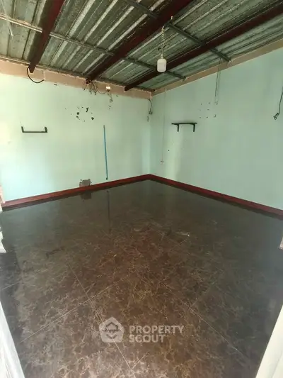 Spacious empty room with tiled floor and metal ceiling, ready for customization.
