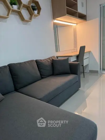 Modern living room with sleek gray sofa and stylish workspace, perfect for urban living.