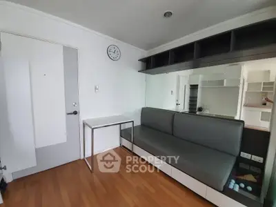 Modern living room with sleek sofa and wall-mounted shelves in a compact apartment.