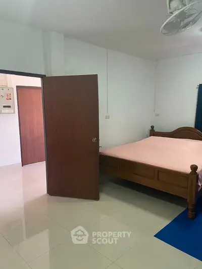 Spacious bedroom with wooden bed and tiled flooring in a modern home