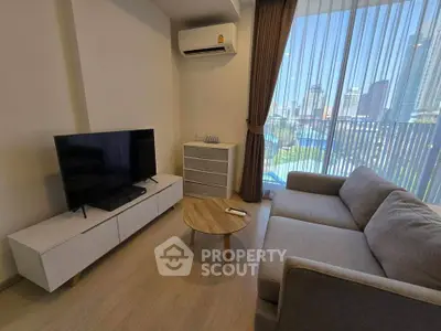 Modern living room with sleek furniture and city view through large windows.
