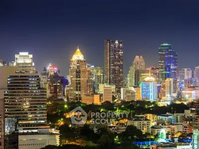 Stunning city skyline view with illuminated skyscrapers and lush greenery at night.