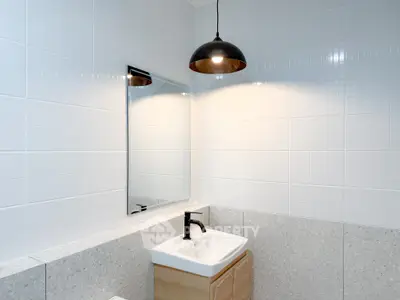 Modern bathroom with sleek sink and stylish lighting in contemporary home.
