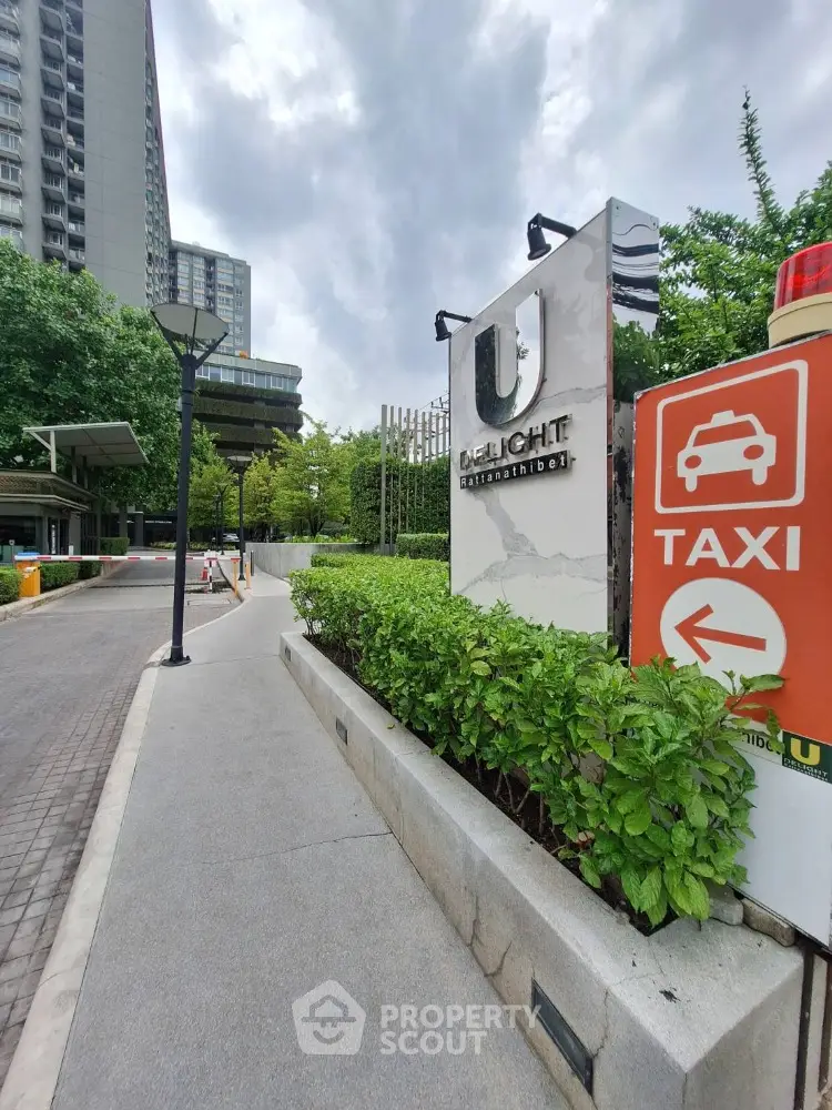 Modern condominium entrance with lush greenery and taxi sign
