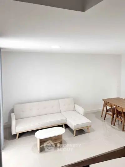 Modern minimalist living room with white sofa and wooden dining set.