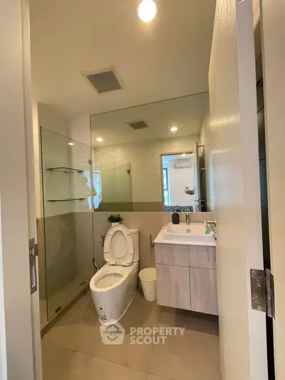 Modern bathroom with glass shower and sleek vanity in contemporary apartment.