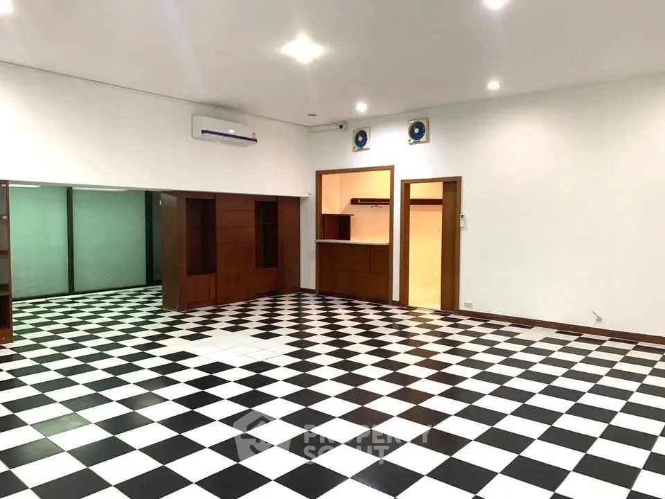 Spacious modern living room with checkered flooring and built-in wooden cabinets