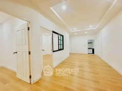 Spacious open-plan living area with modern wooden flooring and recessed lighting.
