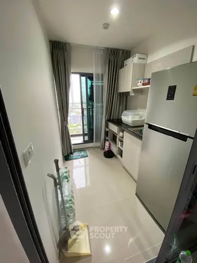 Modern compact kitchen with balcony view in high-rise apartment