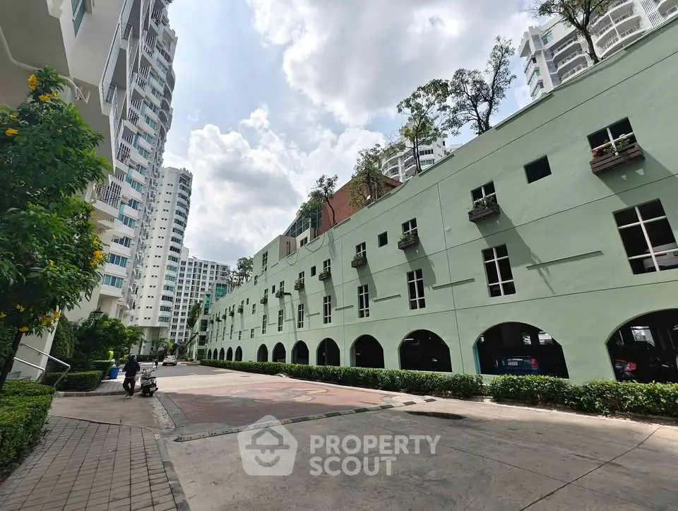 Modern residential building exterior with lush greenery and spacious pathways.