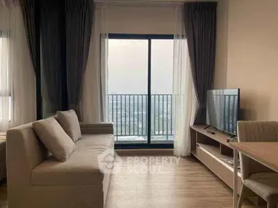 Modern living room with large window and city view, featuring a cozy sofa and sleek TV setup.
