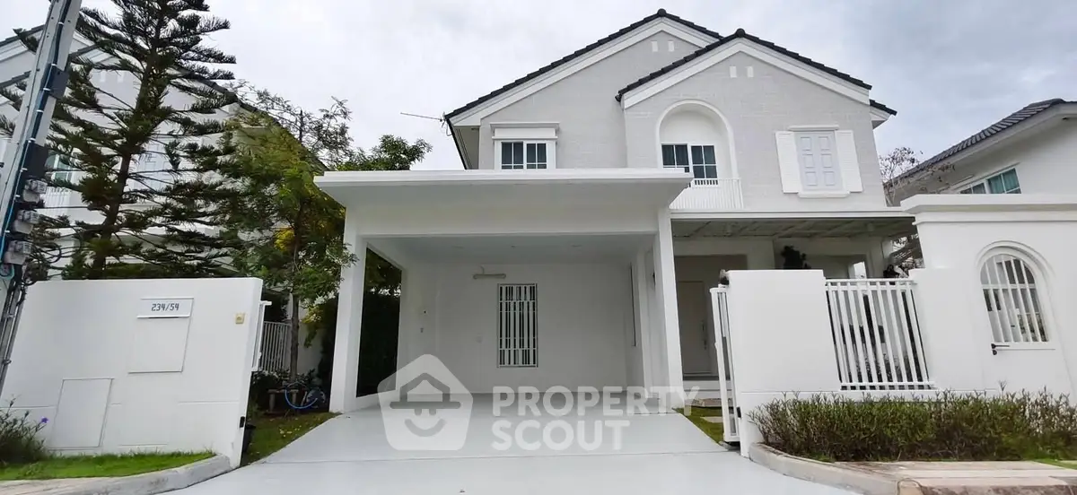 Charming white two-story house with spacious driveway and lush greenery, perfect for family living.