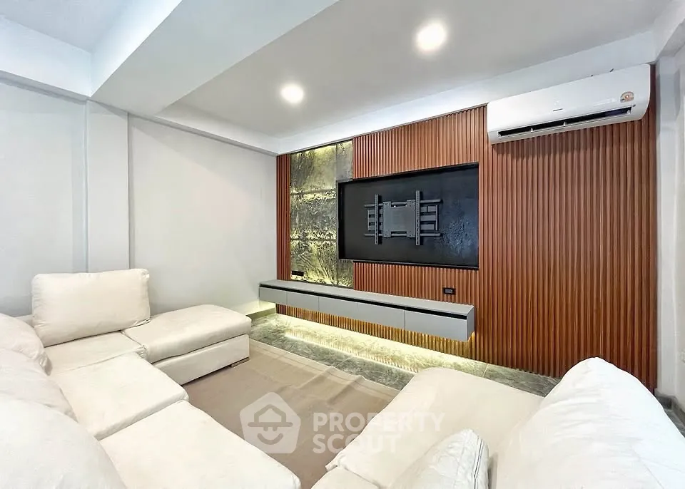 Modern living room with sleek design, featuring a wall-mounted TV space and comfortable white sofas.