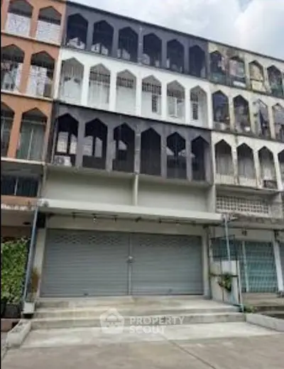 Multi-story commercial building with shutter doors and unique window design.