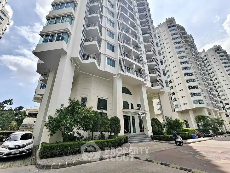 Modern high-rise residential building with lush landscaping and elegant entrance.